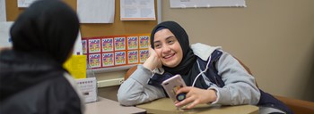 Student smiling with cell phone in Mosaic Center.