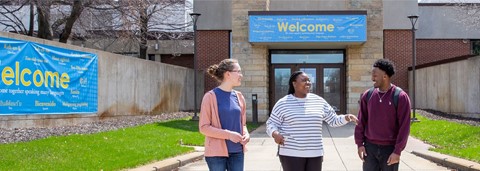 three students talking outside of campus entrance