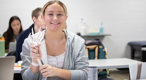 student in lab studying bones of hand 