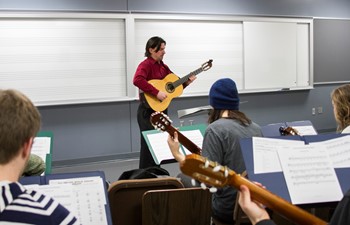 Sam Bergstrom teaching with guitar