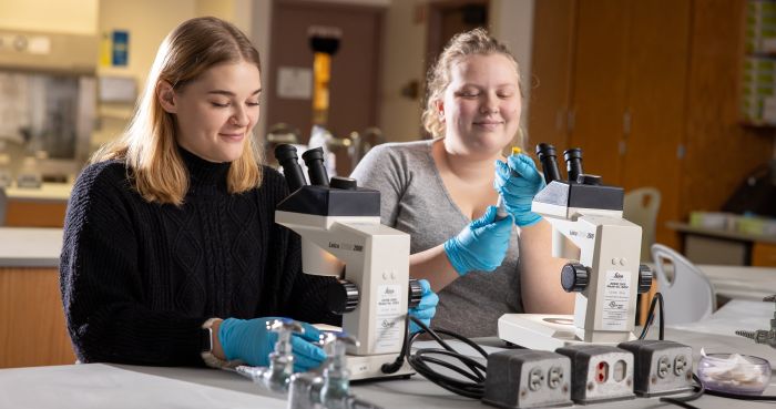 Two Female Students in Science Lab Working with Microscopes