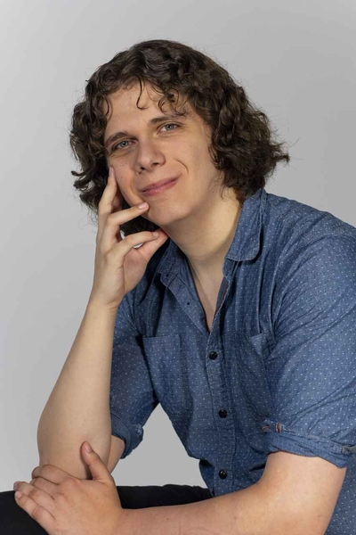 Individual posing with face resting in hand, looking at camera.