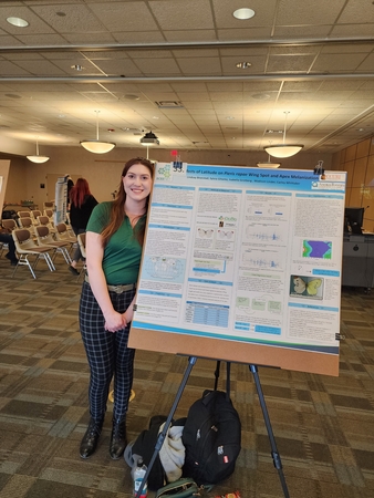 Individual standing next to poster presentation board.