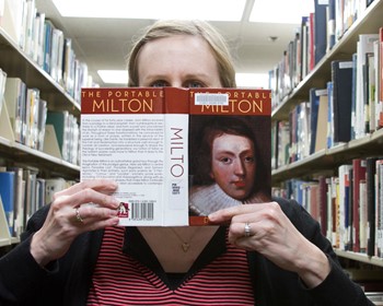 student peering over book