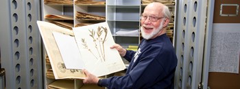 man holding book in herbarium