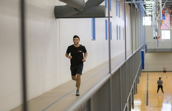 Student smiling and running along track