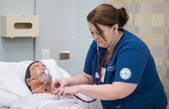 Student uses stethoscope on practice dummy.