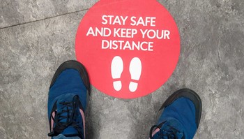 Shoes-near-keep-your-distance-sticker-on-ground