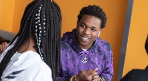 smiling student in purple sweatshirt sitting with another student