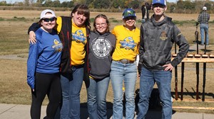 Five individuals standing in sunny setting, smiling at camera