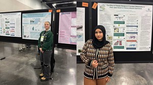 Two individuals standing beside their respective scientific posters at a conference.